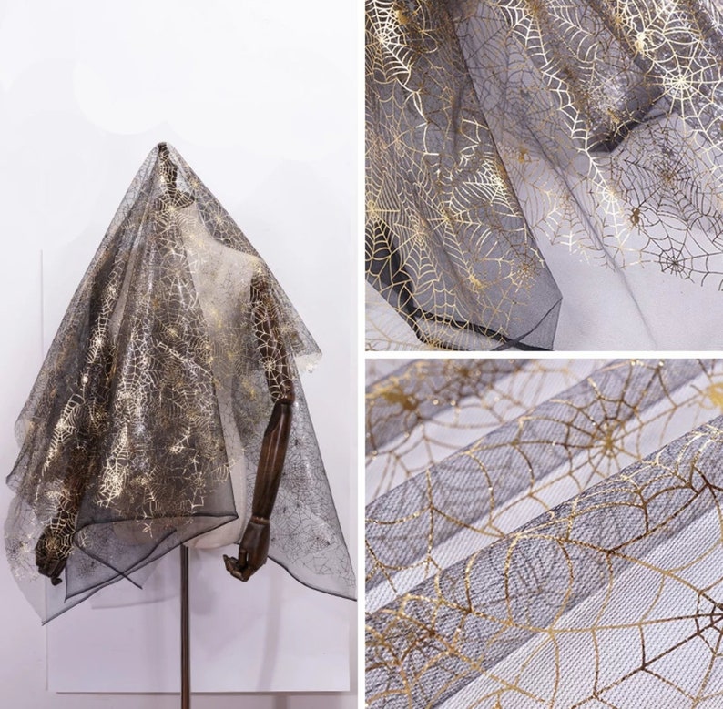 May include: Black and gold spiderweb fabric draped over a mannequin. The sheer material features a delicate gold spiderweb pattern against a black background. The fabric is displayed in multiple views, showcasing its texture and design.