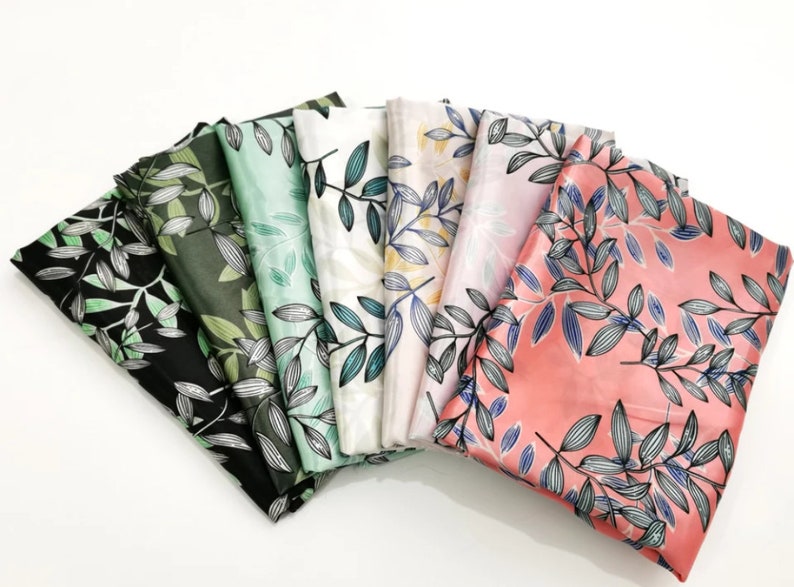 May include: A collection of folded fabric pieces in various colors, each adorned with a botanical leaf pattern. The color palette includes black, green, mint, white, pink, and coral. The leaves are detailed with blue and gray accents.