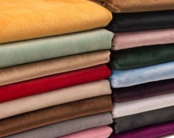 May include: A stack of various colored velvet fabric swatches. Colors include gold, black, pink, green, red, brown, and gray. The fabric appears soft and plush, with a slight sheen.