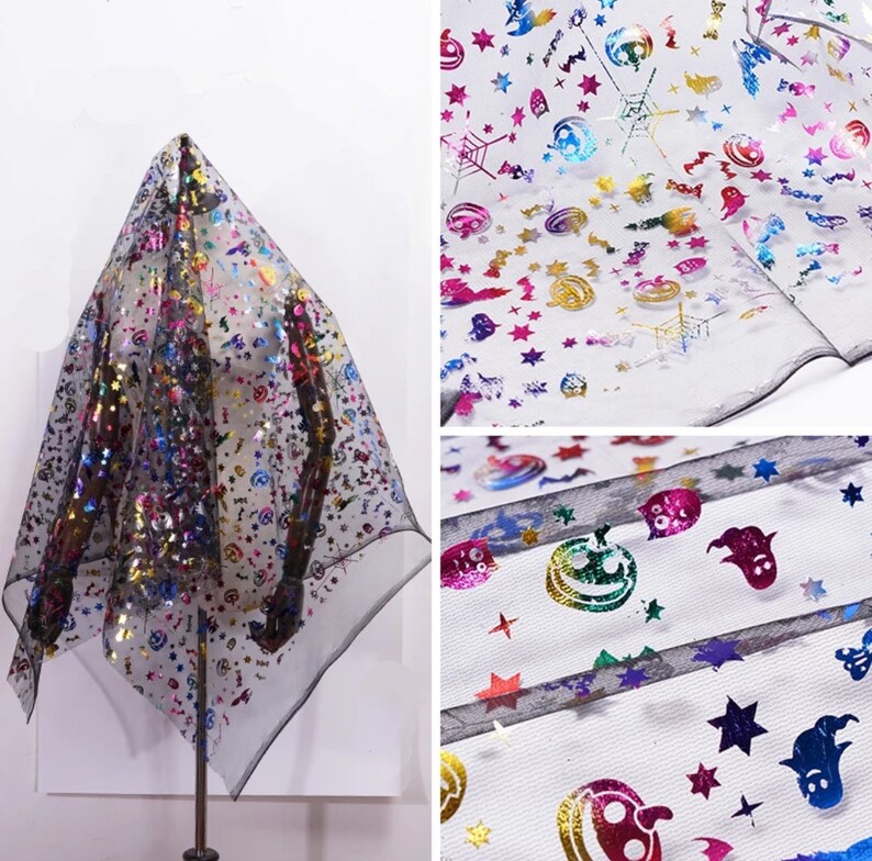 May include: Black sheer fabric featuring a Halloween pattern. The fabric is decorated with colourful holographic images of stars, pumpkins, ghosts, and spiderwebs. The fabric is draped over a stand.
