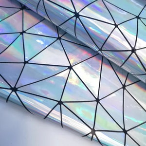 May include: Iridescent geometric patterned fabric. The material has a shiny, reflective surface with a repeating pattern of triangles outlined in black. The fabric reflects a rainbow of colours, creating a holographic effect.