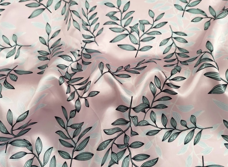 May include: A close-up of a pink fabric with a repeating pattern of stylized leaves. The leaves are in shades of gray and black, with a delicate, hand-drawn appearance. The fabric has a subtle sheen.