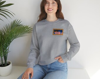 May include: A gray sweatshirt with a small framed image of a woman with a crown on her head. The image is on the left side of the chest of the sweatshirt.