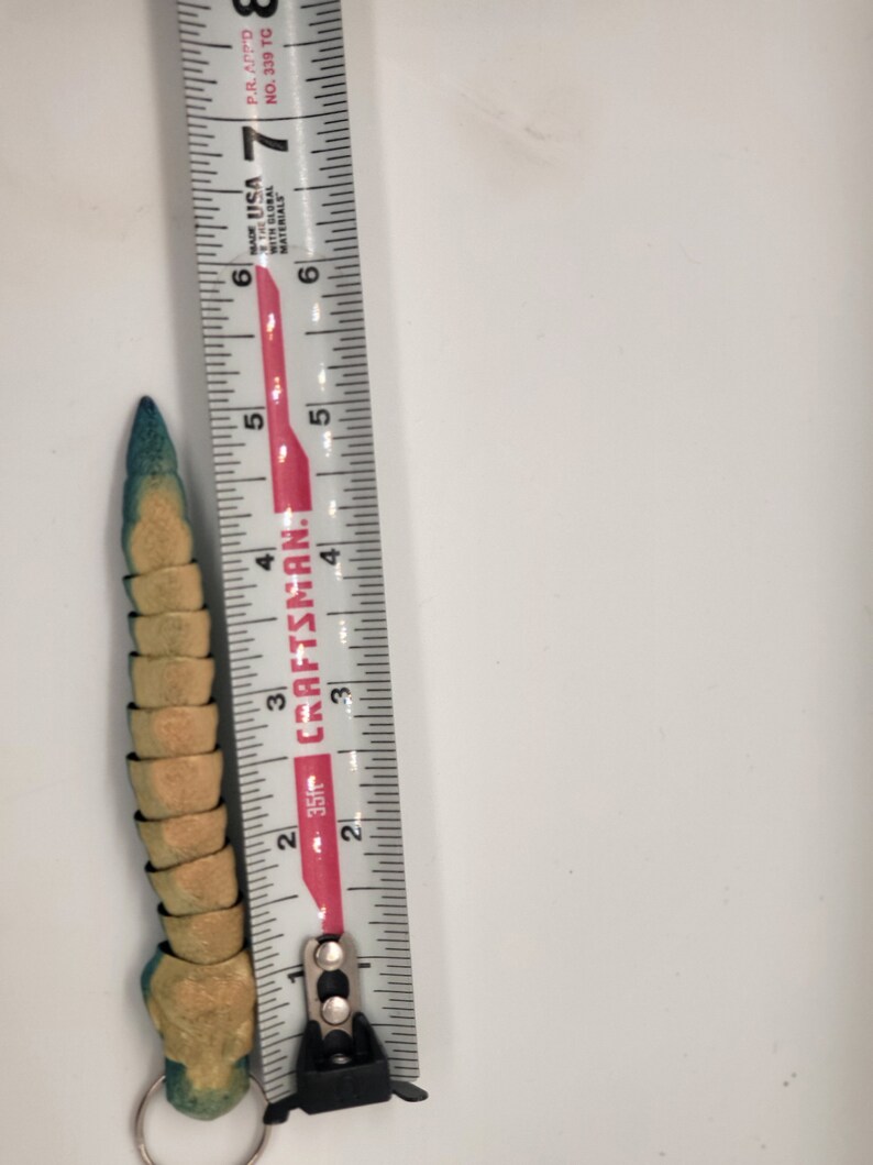 以下が含まれることがあります： 定規に沿って測定された、緑と黄色のセグメントされたおもちゃは、毛虫に似ており、約10cmの長さです。