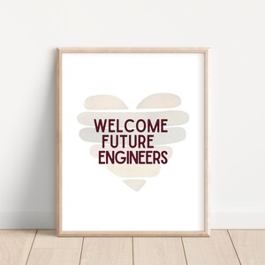 May include: A printable wall art design with a heart shape made of beige and gray watercolor strokes. The text "WELCOME FUTURE ENGINEERS" is written in maroon letters inside the heart.