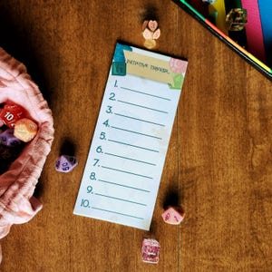 May include: A rectangular initiative tracker card with a tan header labeled Initiative Tracker and ten numbered lines for game tracking. The card is surrounded by various multi-sided polyhedral dice in colors including red, orange, purple, and pink.