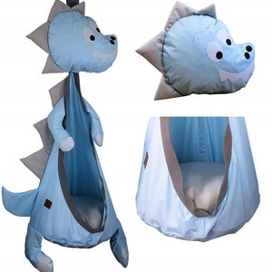 Könnte beinhalten: Ein blauer und grauer Dinosaurier-förmiger Hängesessel für Kinder. Der Sessel hat einen weichen, plüschigen Stoff und einen bequemen, gepolsterten Sitz. Er ist perfekt für den Innen- oder Außenbereich.