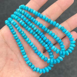 Può includere: Una collana composta da piccole perline rotonde di colore blu turchese brillante. Le perline sono uniformi per forma e dimensione, caratterizzate da una finitura liscia e lucida con sottili variazioni di colore naturale lungo tutto il filo.