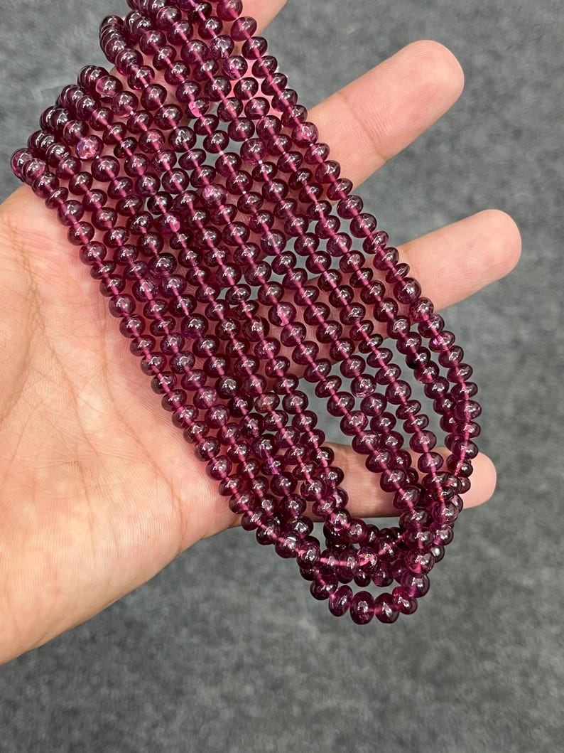 May include: A strand of deep red gemstone beads. The beads are round and smooth, and they are strung on a clear thread. The beads are approximately 4mm in diameter.