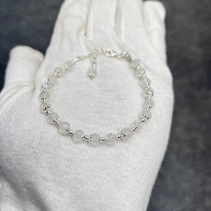 Peut inclure: Un bracelet en argent avec des perles de pierre de lune blanche. Le bracelet a un petit fermoir réglable.