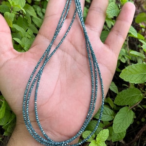 K&ouml;nnte beinhalten: Eine Halskette aus blauen Diamantperlen. Die Halskette ist geschichtet und scheint aus vielen kleinen Perlen zu bestehen.