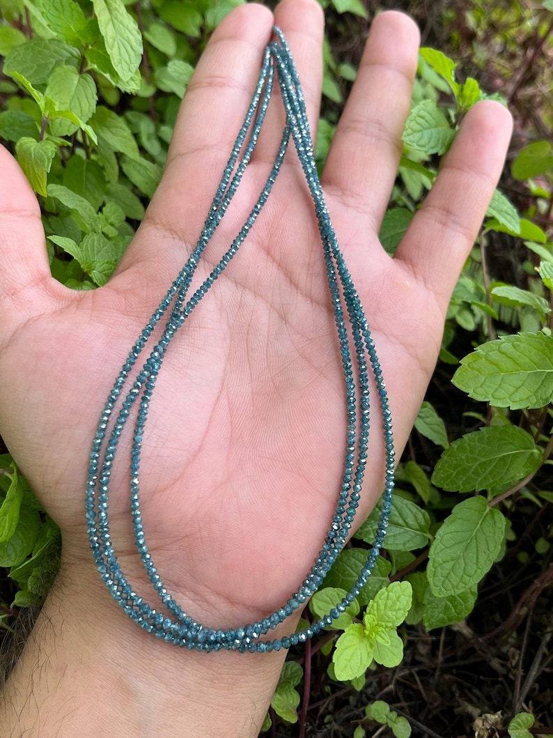K&ouml;nnte beinhalten: Eine Halskette aus blauen Diamantperlen. Die Halskette ist geschichtet und scheint aus vielen kleinen Perlen zu bestehen.
