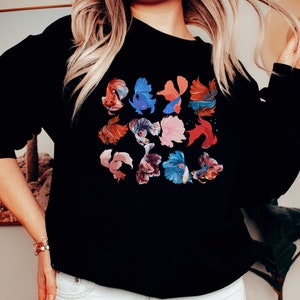 May include: Black sweatshirt with a colorful graphic print of multiple betta fish. The fish are in various shades of red, blue, and pink.