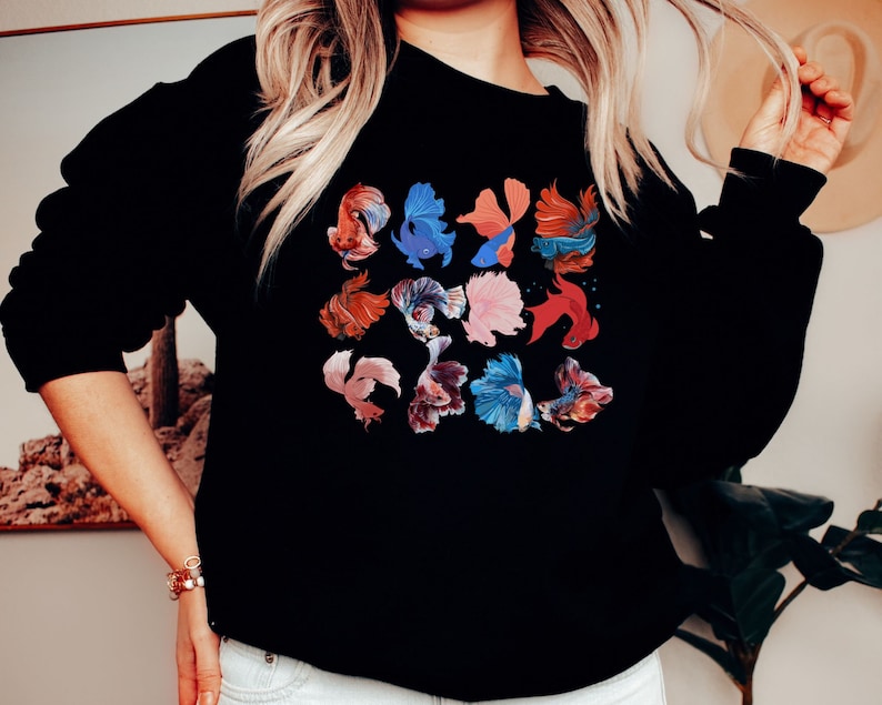 May include: Black sweatshirt with a colorful graphic print of multiple betta fish. The fish are in various shades of red, blue, and pink.