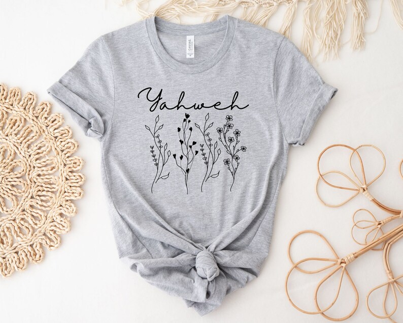 May include: Gray t-shirt with the word "Yahweh" in black cursive lettering and a floral design below it.
