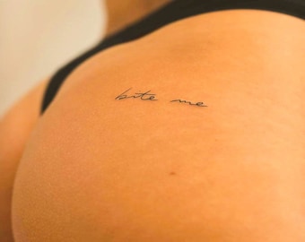 Bite Me lettering tattoo on pelvis