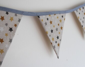 May include: A beige fabric bunting with a blue trim. The bunting is decorated with gold and gray stars.