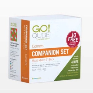 May include: A white box with a green and orange design. The box is labelled "GO! QUBE Corners Companion Set" and features a picture of a quilt block. The box includes 10 free patterns, 4 dies, a cutting mat, a pattern book, a step-by-step DVD, and a GO! QUBE 9" block.