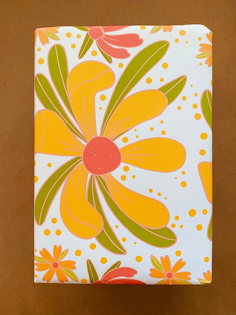 May include: White wrapping paper with a repeating pattern of yellow, orange, and green stylized flowers. The flowers have a retro 1970s aesthetic.