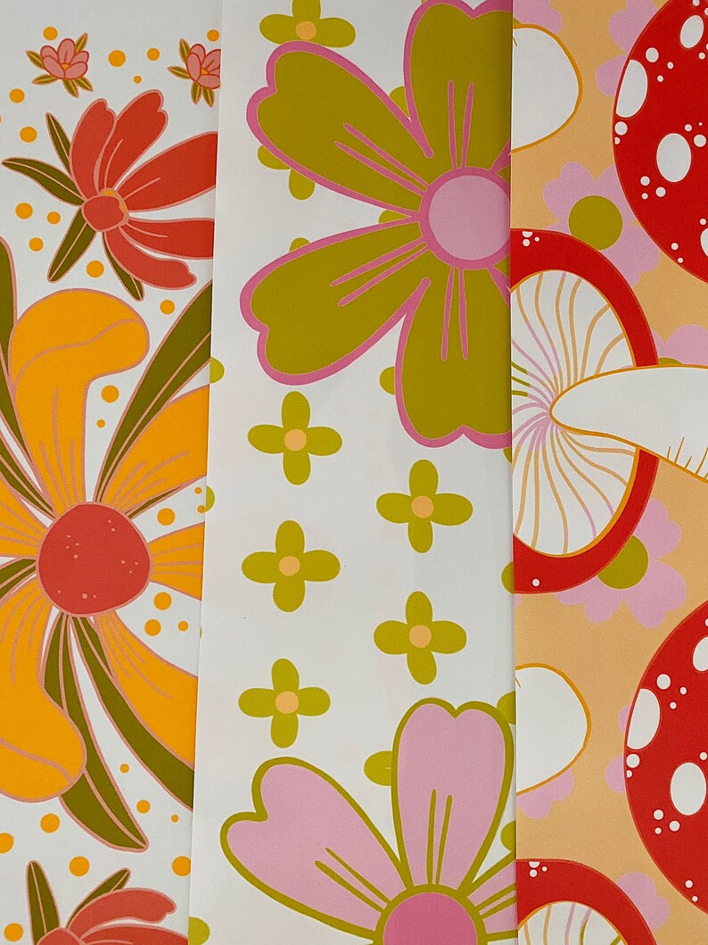 May include: Three different patterned fabric swatches. The first swatch features a yellow and orange flower with green leaves on a white background. The second swatch features a pink and green flower on a white background. The third swatch features a red and white mushroom on a peach background.