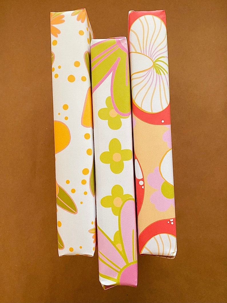 May include: Three wrapped canvases with different retro floral patterns. The canvases are white with pink, yellow, green, and orange flowers and swirls.