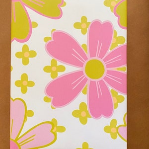 May include: White wrapping paper with a pink and yellow floral pattern. The flowers are stylized and have a retro look.