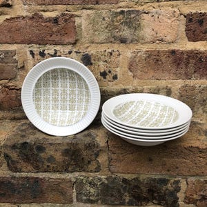 May include: A set of six white ceramic bowls with a green and white geometric pattern. The bowls are stacked on top of each other.