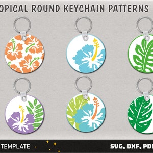 May include: Six round keychain templates featuring tropical designs. The designs include hibiscus flowers, palm leaves, and monstera leaves in various colours, including orange, blue, green, and purple.