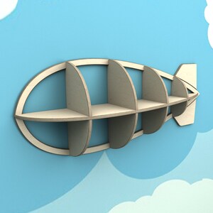 May include: A wooden shelf shaped like an airship with five compartments. The shelf is painted in a light wood color and is mounted on a blue wall.