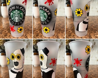 May include: A frosted plastic tumbler with a black and white clown design, yellow sunflowers, and red splatter accents. The tumbler features the text "Clown Cafe Coffee" in a circular logo.