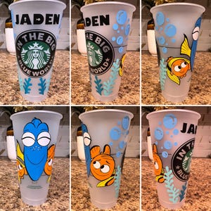 Może przedstawiać: Przezroczysty plastikowy kubek z pokrywką, z motywem inspirowanym filmem "Gdzie jest Nemo". Projekt zawiera imię "JADEN", logo Starbucks oraz wizerunki ryb i bąbelków. Kubek ma niebieską i turkusową kolorystykę.