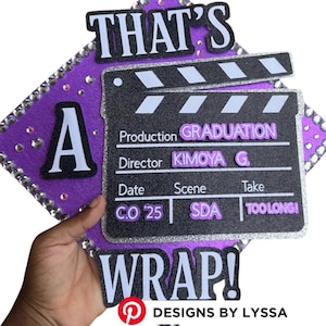 May include: A graduation cap decorated with a film clapboard design. The cap is purple with silver accents and the text "THAT'S A WRAP!" The clapboard reads "GRADUATION" and "C.O '25". The Etsy shop name "LYSSACREATIONSSHOP" is also visible.