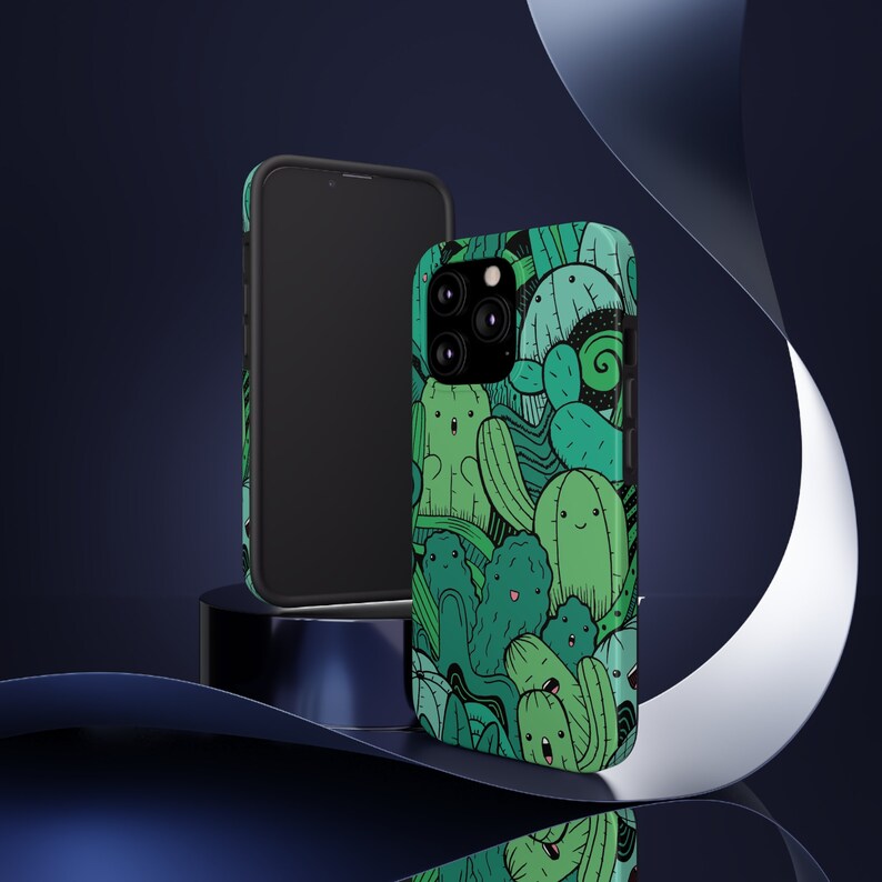 Peut inclure: Une coque de t&eacute;l&eacute;phone noire avec un motif de cactus vert et noir. La coque a une d&eacute;coupe pour l'objectif de l'appareil photo.