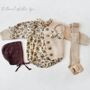 May include: A five-piece baby outfit set in oatmeal color. The set includes a floral print romper, a knitted cardigan, a knitted hat, and a pair of tights. The outfit is perfect for winter.