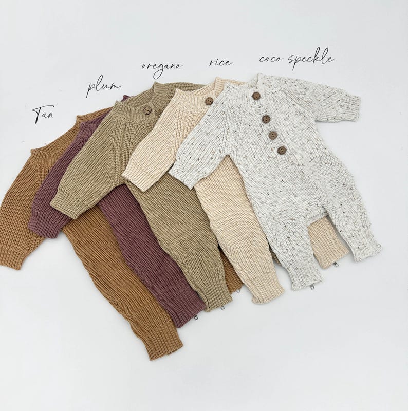 May include: Five knitted baby onesies in different colors and patterns. The onesies are arranged in a row, with the lightest color at the top and the darkest color at the bottom. The colors are: tan, plum, oregano, rice, and coco speckle.