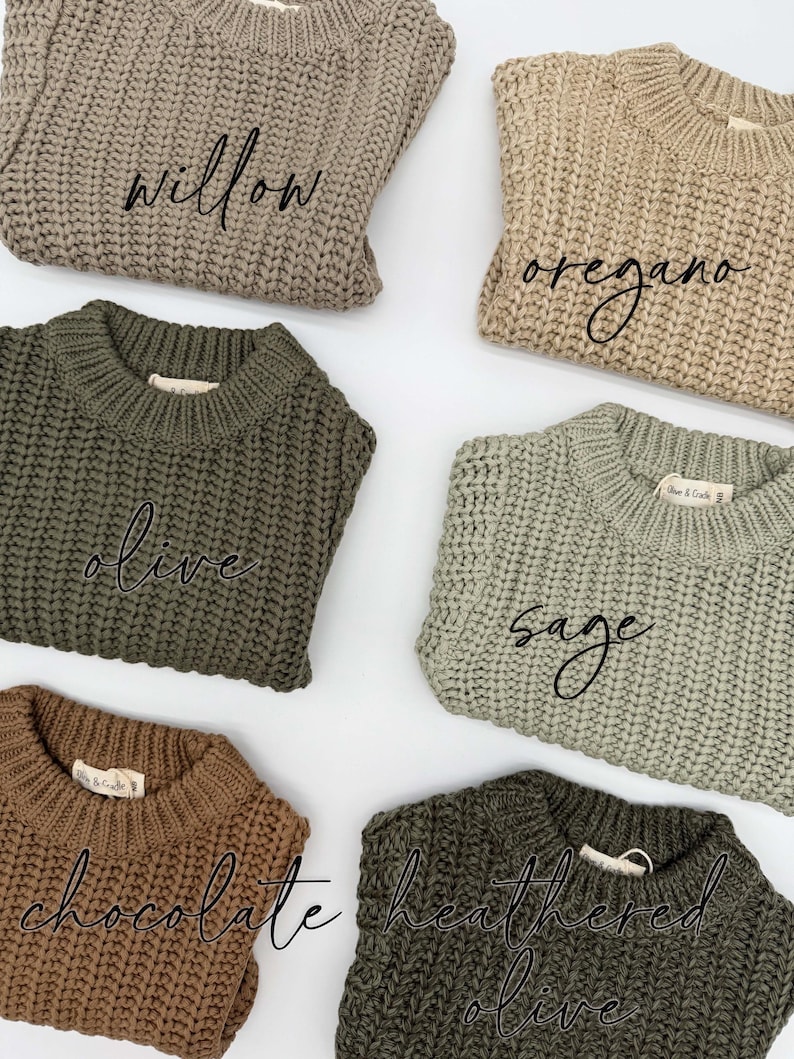 May include: Six chunky knit sweaters in various earth tones, each featuring a ribbed crew neckline and a woven brand label. The colors are labeled as willow, oregano, olive, sage, chocolate, and heathered olive in black script text on each.