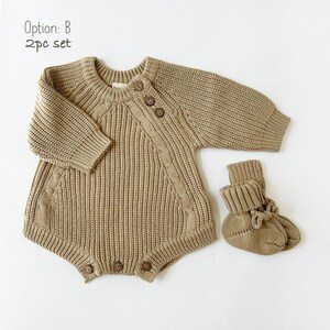 May include: A two-piece knitted baby outfit in a light brown color. The outfit includes a long-sleeved sweater with button closures and matching booties.