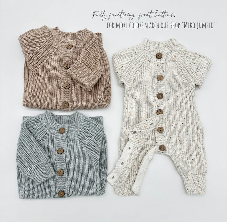 May include: Three knitted baby onesies in different colors: beige, white with black speckles, and light blue. Each onesie has a button closure down the front and is made of a soft, textured knit fabric.