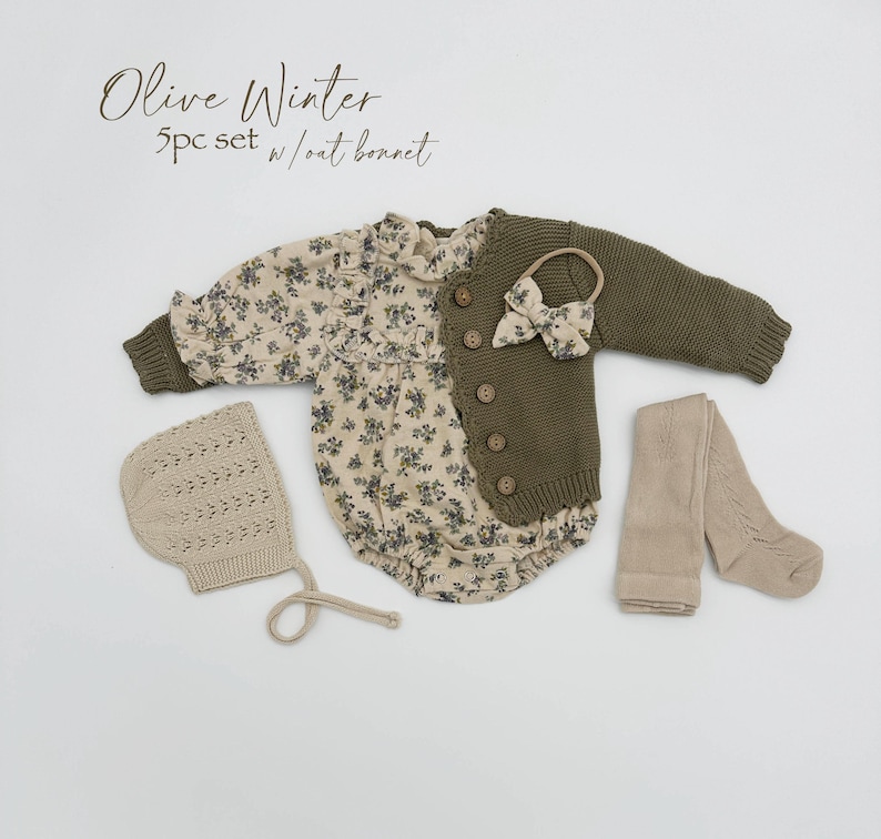 May include: Olive Winter 5pc set w/oat bonnet. A baby outfit set with a floral print romper, a green cardigan, a pair of tights, and a crocheted bonnet.