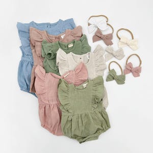 Op de afbeelding: Een set van zes baby rompers met geruite mouwen in verschillende kleuren, waaronder lichtblauw, roze, groen en beige. De rompers zijn gemaakt van een zachte, linnenachtige stof. De set bevat ook vier haarbandjes in verschillende kleuren.