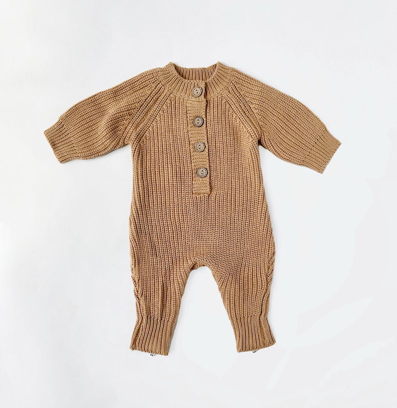 May include: A brown knitted baby onesie with a button closure at the neckline. The onesie has long sleeves and a ribbed texture.