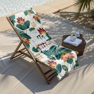 Puede incluir: Una toalla de playa blanca con un diseño floral verde y rojo. La toalla tiene las palabras "Our High Herbs" impresas en blanco.