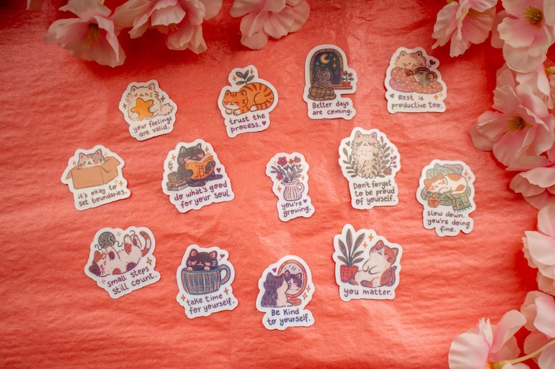 May include: A collection of thirteen individual die-cut stickers featuring various illustrated cats in different poses and settings, each accompanied by motivational text such as 'your feelings are valid', 'trust the process', and 'you matter'.