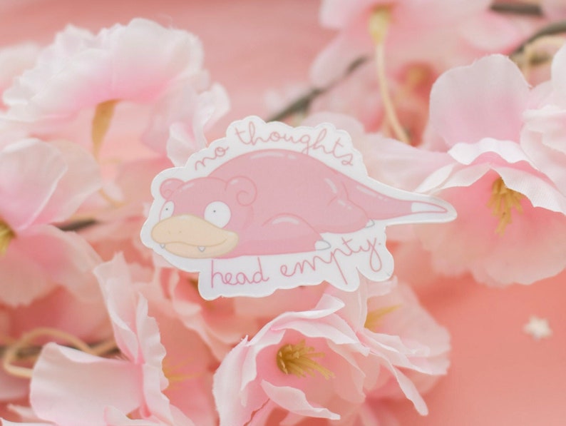 May include: A pink sticker with a cartoon pink pig-like creature with the text "no thoughts head empty". The sticker is on a background of pink flowers.