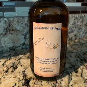 May include: A brown glass bottle with a black cap, labeled "Colloidal Silver." The label includes text about the product's ingredients and the manufacturer, "The Silver Solution" in Lexington, SC, USA. The bottle contains 16 fl oz.