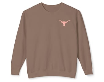 Pode incluir: Uma camisa de manga comprida marrom com um gráfico de cabeça de touro Longhorn rosa na frente.