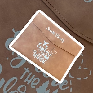 May include: A brown leather folder with a white inscription that reads "Explore the World" and "Smith Family".