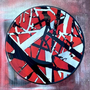 May include: A black vinyl record with a red, white, and black geometric pattern. The record is a popular design for music lovers.