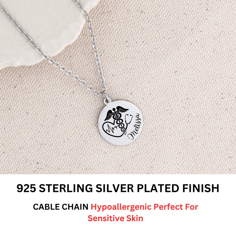 May include: A silver necklace with a round pendant featuring a medical symbol, a heart with a heartbeat line, and the name "Melissa". The necklace is on a cable chain and is hypoallergenic.