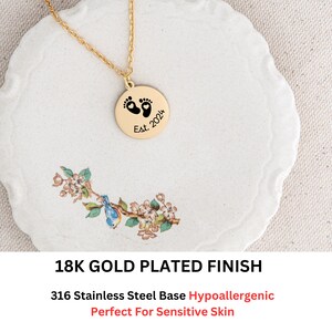May include: Gold plated necklace with a round pendant featuring a footprint design and the text "Est. 2024".
